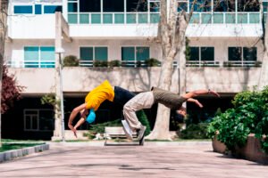 Two multi-ethnic friends dancing in the park and doing coordinated break dance moves.
